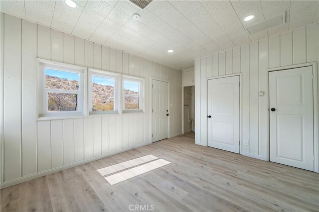 unfurnished bedroom featuring wooden walls and light wood-type flooring