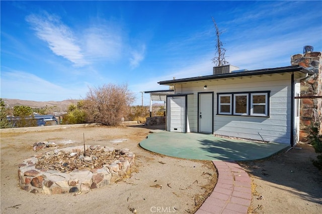 rear view of house featuring a mountain view and a patio area