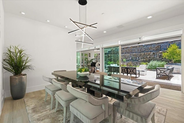 dining space with a notable chandelier and light hardwood / wood-style flooring