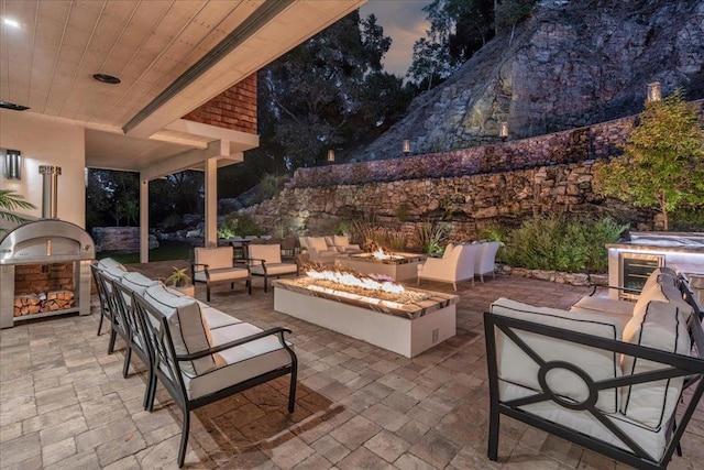 patio terrace at dusk featuring area for grilling and an outdoor living space with a fire pit