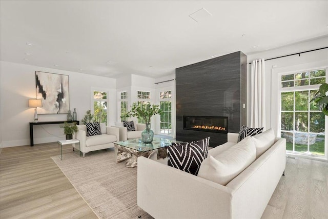 living room with a large fireplace and light wood-type flooring