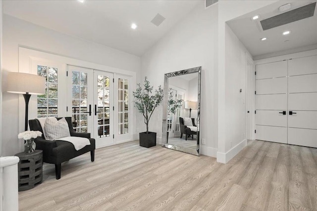 sitting room with light hardwood / wood-style flooring, high vaulted ceiling, and french doors