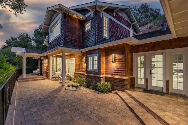 back house at dusk with french doors and a patio area