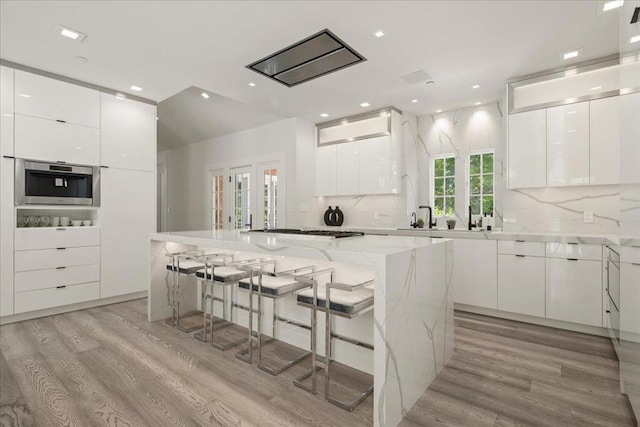 kitchen featuring a kitchen island, a breakfast bar area, and white cabinets