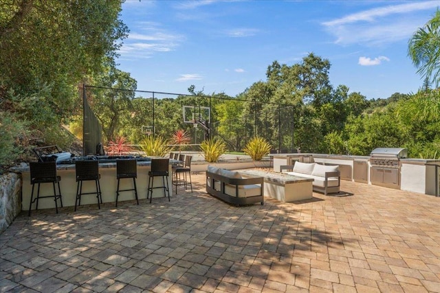 view of patio with area for grilling, exterior bar, an outdoor living space with a fire pit, and an outdoor kitchen