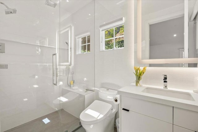 bathroom with toilet, vanity, decorative backsplash, and a shower with shower door