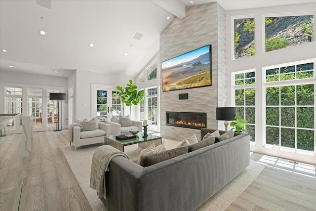 living room featuring a fireplace, light hardwood / wood-style flooring, high vaulted ceiling, and french doors