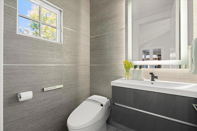 bathroom featuring vanity, toilet, tile walls, and backsplash