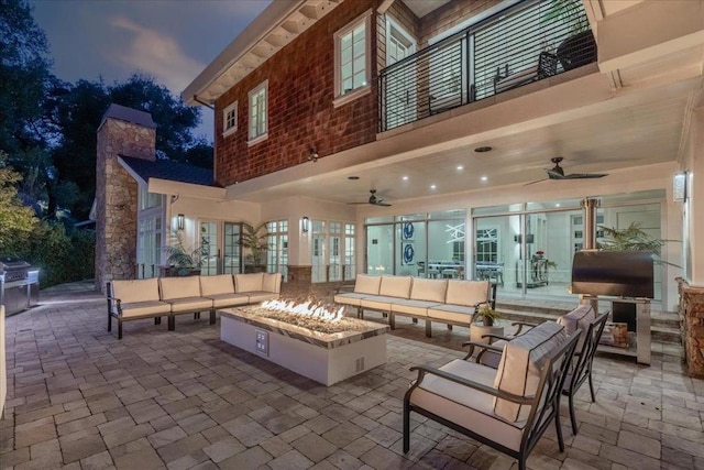 patio terrace at dusk with an outdoor living space with a fire pit and ceiling fan