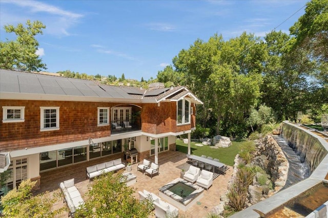 back of house with an outdoor living space, solar panels, and a patio area