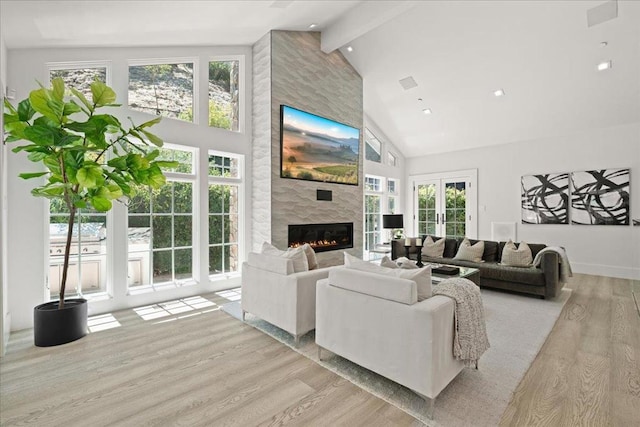 living room with beamed ceiling, a healthy amount of sunlight, a fireplace, and light hardwood / wood-style floors