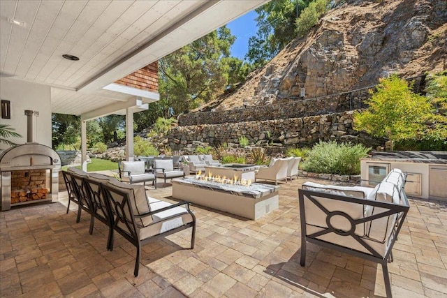 view of patio / terrace featuring exterior kitchen and an outdoor living space with a fire pit