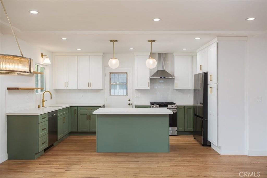 kitchen with gas range, dishwasher, wall chimney range hood, refrigerator, and green cabinetry