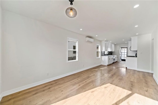 unfurnished living room with a wall mounted AC and light wood-type flooring