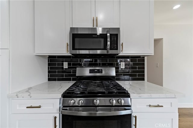 kitchen with white cabinets, decorative backsplash, stainless steel appliances, and light stone counters