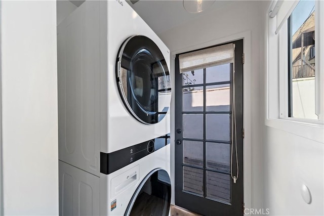 laundry area with stacked washer / drying machine and a healthy amount of sunlight