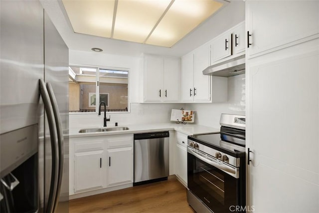 kitchen with hardwood / wood-style flooring, appliances with stainless steel finishes, white cabinetry, and sink