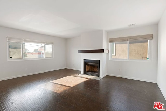 unfurnished living room featuring dark hardwood / wood-style flooring and a wealth of natural light