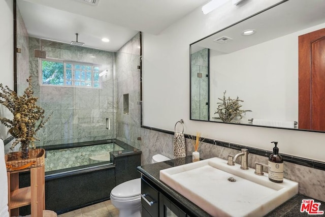 bathroom featuring vanity, toilet, and tile walls