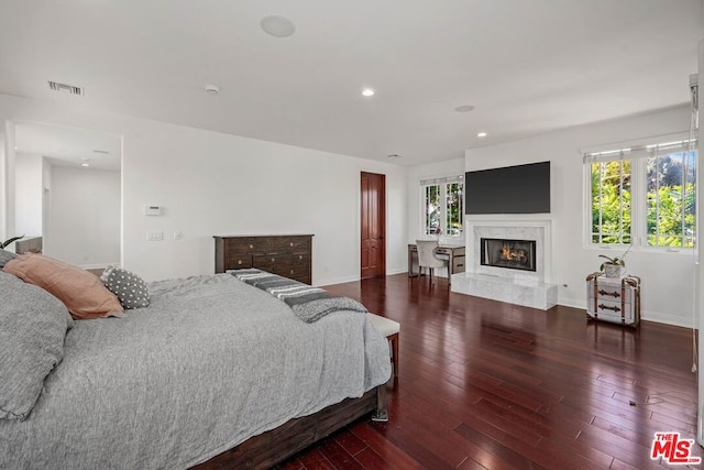 bedroom with dark hardwood / wood-style flooring and a high end fireplace