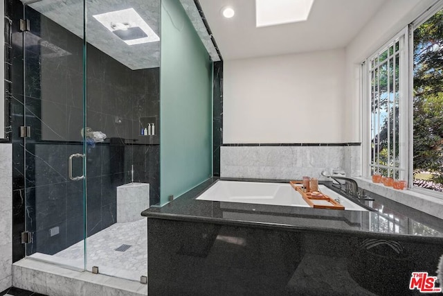 bathroom featuring a skylight, independent shower and bath, and sink