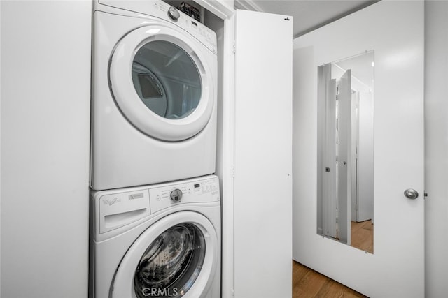 washroom with wood-type flooring and stacked washer / drying machine