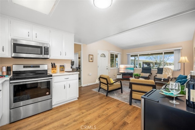 kitchen with white cabinets, light hardwood / wood-style floors, lofted ceiling, and stainless steel appliances