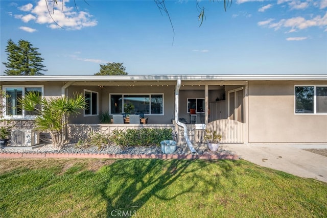 ranch-style house featuring covered porch and a front lawn