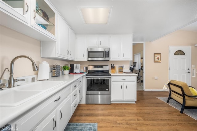 kitchen with sink, white cabinets, stainless steel appliances, and wood-type flooring