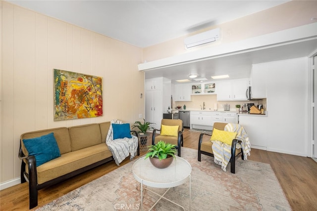 living room with a wall unit AC, wooden walls, sink, and light hardwood / wood-style floors