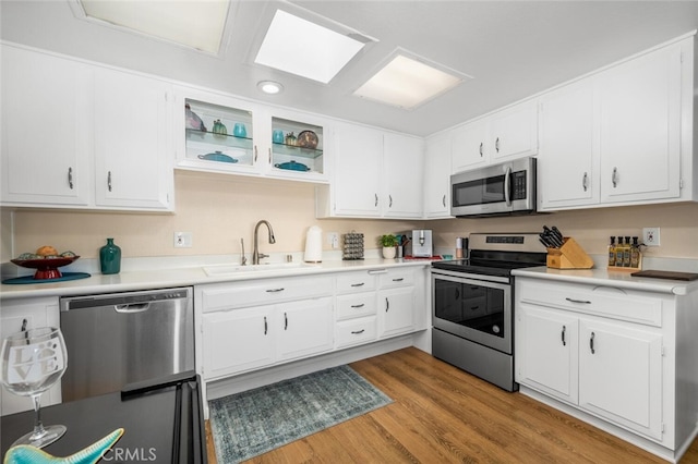 kitchen with light wood-type flooring, white cabinetry, sink, and appliances with stainless steel finishes