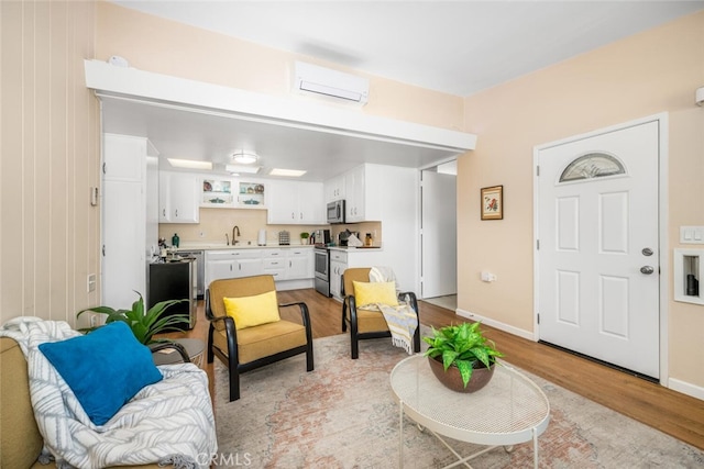 living room with an AC wall unit, sink, and light hardwood / wood-style floors