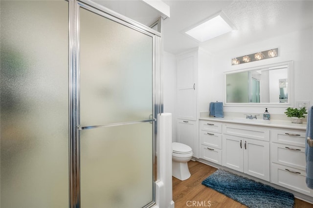 bathroom featuring toilet, vanity, wood-type flooring, and walk in shower