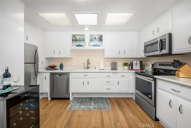 kitchen with light wood-type flooring, white cabinetry, sink, and appliances with stainless steel finishes