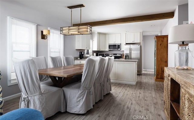 dining space with beam ceiling and light wood-type flooring