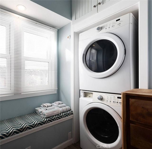 laundry room featuring stacked washer / drying machine and cabinets