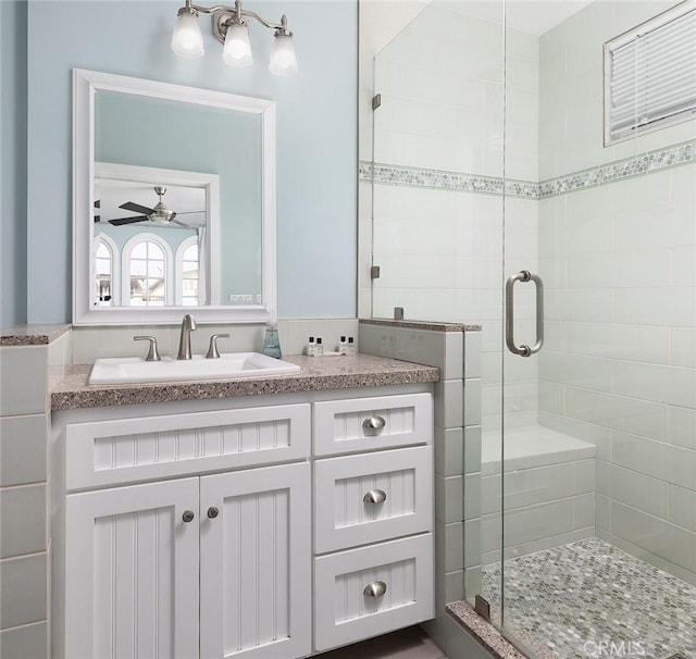 bathroom featuring walk in shower, vanity, and ceiling fan