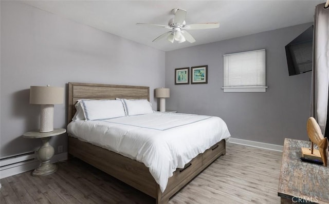 bedroom featuring ceiling fan, baseboard heating, and light hardwood / wood-style flooring