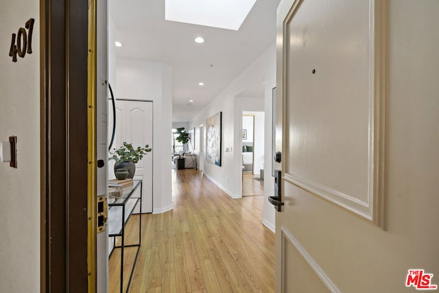 hallway featuring light wood-type flooring and a skylight