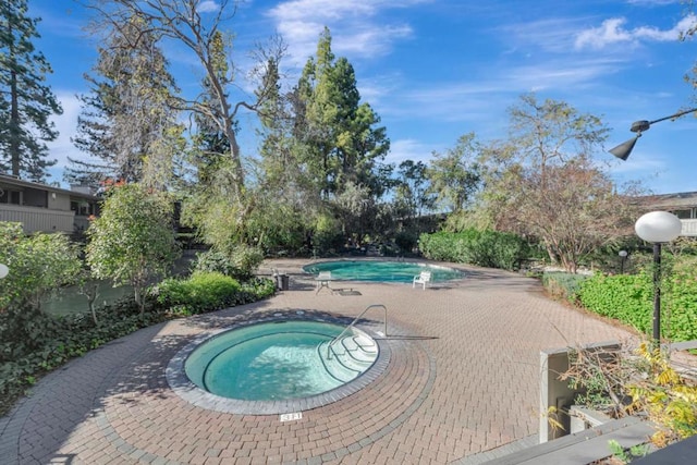 view of swimming pool featuring a hot tub and a patio