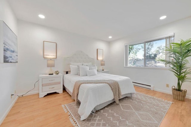 bedroom with a baseboard heating unit and light hardwood / wood-style floors