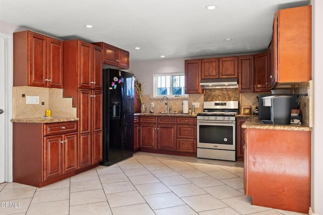 kitchen featuring sink, black fridge with ice dispenser, light stone counters, and gas range