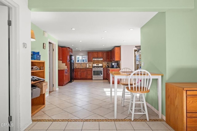 kitchen featuring backsplash, black fridge, stainless steel stove, and light tile patterned flooring