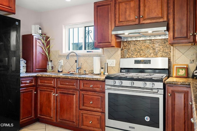 kitchen with backsplash, stainless steel gas stove, light stone countertops, and sink