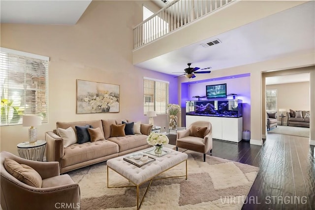 living room with dark hardwood / wood-style floors, ceiling fan, and a towering ceiling