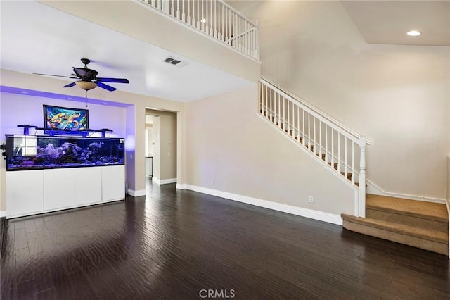 unfurnished living room with ceiling fan, dark hardwood / wood-style flooring, and a towering ceiling