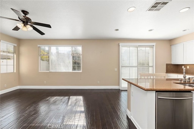 kitchen featuring dark wood-type flooring, stainless steel dishwasher, a healthy amount of sunlight, and white cabinets