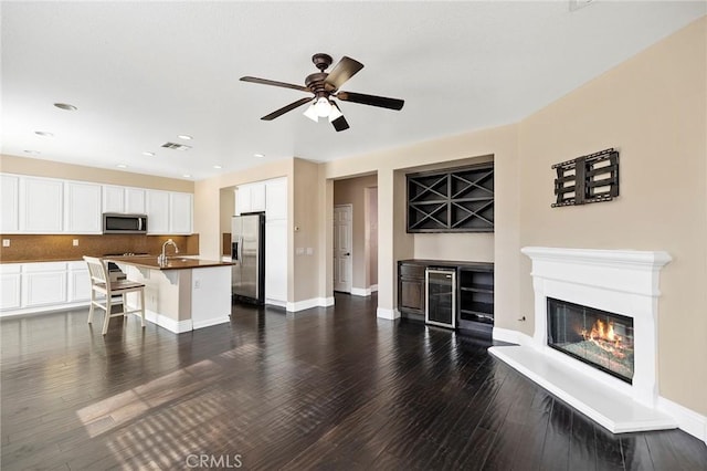 living room with ceiling fan, beverage cooler, dark hardwood / wood-style flooring, and sink