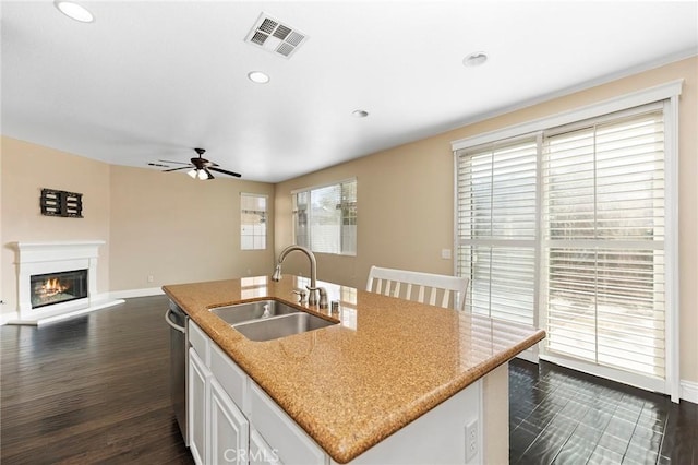 kitchen with dishwasher, white cabinetry, sink, a kitchen island with sink, and dark wood-type flooring