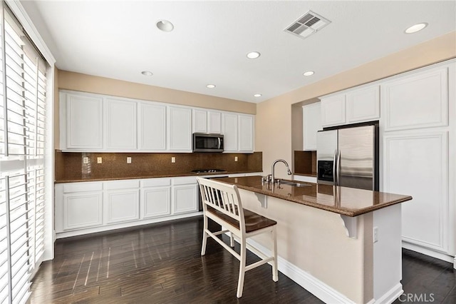 kitchen with tasteful backsplash, white cabinetry, a breakfast bar area, stainless steel appliances, and a center island with sink